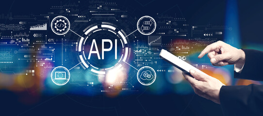 API - application programming interface concept with businessman using a tablet computer at night