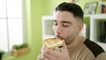 Sticker - Young arab man eating toast sitting on table at home