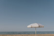 Beach umbrella on beach sand in front of blue sea and sky. Minimal summer holidays vacation concept