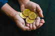close up hand holding gold coins with a bitcoin symbol and trading graph in the background