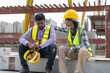 © Supachai - Asian Indian man worker feeling sad and upset while sitting at construction site. Female worker colleague supporting and consolation him.