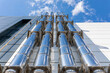 Chrome ventilation pipes on the outer wall of a black-and-white industrial building against a blue sky background. Gas heating turbo boiler. Bottom-up view.