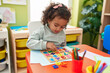 © Krakenimages.com - Adorable hispanic girl playing with maths puzzle game sitting on table at kindergarten