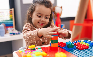 Canvas Print - Adorable hispanic girl playing with construction blocks sitting on table at kindergarten