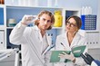 © Krakenimages.com - Man and woman wearing scientist uniform holding sample writing on notebook at laboratory