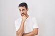 © Krakenimages.com - Handsome hispanic man standing over white background thinking worried about a question, concerned and nervous with hand on chin