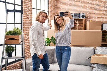 Canvas Print - Man and woman couple make selfie by the smartphone sitting on sofa at new home