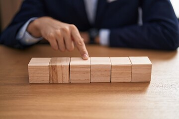 Poster - Young blond man business worker sitting on table with wooden cubes at office