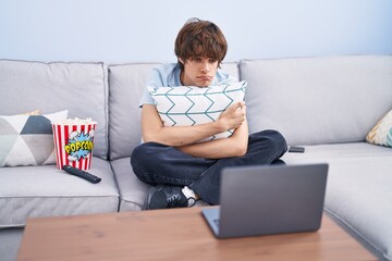 Wall Mural - Hispanic young man watching a horror movie in the laptop depressed and worry for distress, crying angry and afraid. sad expression.