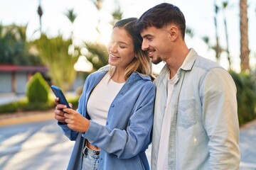 Poster - Young man and woman couple smiling confident using smartphone at street