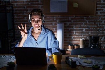 Poster - Beautiful brunette woman working at the office at night showing and pointing up with fingers number three while smiling confident and happy.