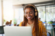 © CarlosBarquero - Young black African college girl studying online on her laptop. Smiling applied Latin woman taking an online virtual class sitting in campus cafeteria. Close-up portrait happy woman in concentration.