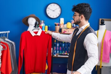 Canvas Print - Young hispanic man tailor holding clothes on rack at sewing studio