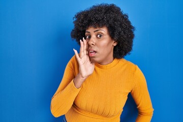 Sticker - Black woman with curly hair standing over blue background hand on mouth telling secret rumor, whispering malicious talk conversation