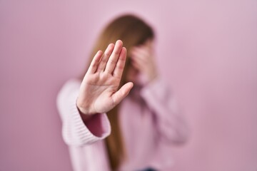 Poster - Young caucasian woman standing over pink background covering eyes with hands and doing stop gesture with sad and fear expression. embarrassed and negative concept.