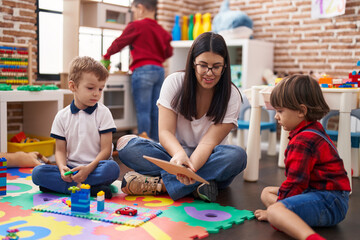 Teacher with group of boys sitting on floor having lesson at kindergarten