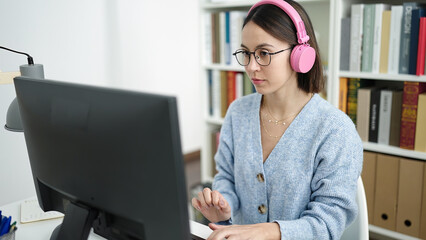 Young beautiful hispanic woman student using computer studying at library university