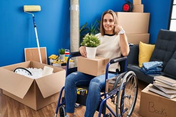 Poster - Young woman sitting on wheelchair moving to a new home pointing with hand finger to face and nose, smiling cheerful. beauty concept