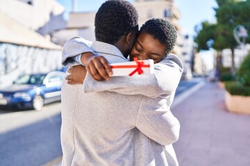 Sticker - Man and woman couple hugging each other surprise with gift at street