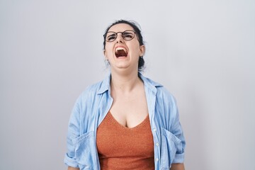 Canvas Print - Young modern girl with blue hair standing over white background angry and mad screaming frustrated and furious, shouting with anger. rage and aggressive concept.