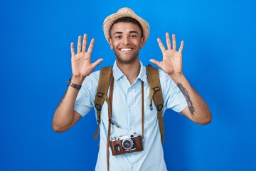 Sticker - Brazilian young man holding vintage camera showing and pointing up with fingers number ten while smiling confident and happy.