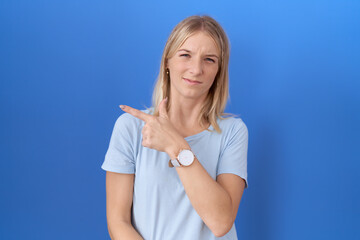 Wall Mural - Young caucasian woman wearing casual blue t shirt pointing aside worried and nervous with forefinger, concerned and surprised expression