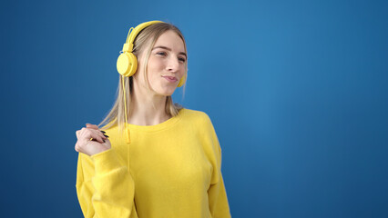 Sticker - Young blonde woman dancing wearing headphones over isolated blue background