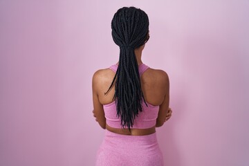 Sticker - African american woman with braids wearing sportswear over pink background standing backwards looking away with crossed arms