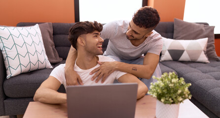 Poster - Two hispanic men couple using laptop sitting on sofa at home