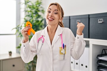 Poster - Hispanic doctor woman holding awareness orange ribbon screaming proud, celebrating victory and success very excited with raised arms