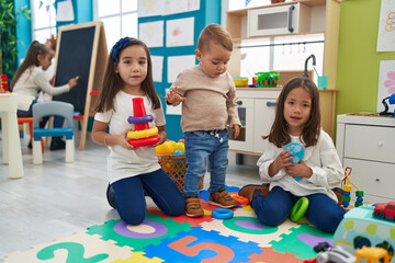 Wall Mural - Group of kids playing with hoops toys sitting on floor at kindergarten