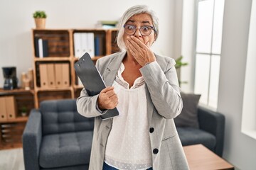 Poster - Middle age woman with grey hair at consultation office shocked covering mouth with hands for mistake. secret concept.