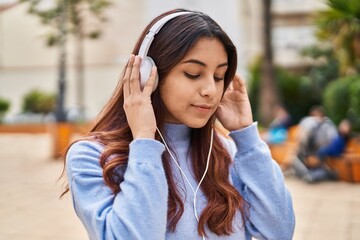 Poster - Young hispanic woman listening to music at park