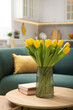 © New Africa - Spring interior. Bouquet of beautiful yellow tulips and books on wooden table in living room