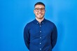 © Krakenimages.com - Young hispanic man wearing glasses over blue background with a happy and cool smile on face. lucky person.