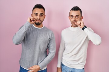 Poster - Homosexual couple standing over pink background mouth and lips shut as zip with fingers. secret and silent, taboo talking