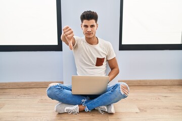 Sticker - Young hispanic man using laptop at home looking unhappy and angry showing rejection and negative with thumbs down gesture. bad expression.