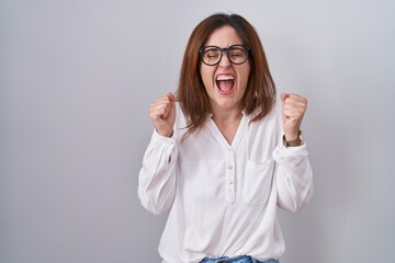 Sticker - Brunette woman standing over white isolated background excited for success with arms raised and eyes closed celebrating victory smiling. winner concept.