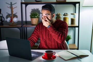 Poster - Young hispanic man with beard using computer laptop at night at home shocked covering mouth with hands for mistake. secret concept.