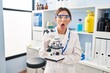 © Krakenimages.com - Young brunette woman working at scientist laboratory with microscope afraid and shocked with surprise and amazed expression, fear and excited face.