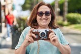 Fototapeta Paryż - Senior woman tourist smiling confident holding camera at street