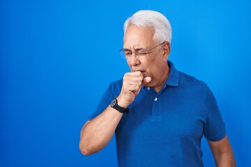 Wall Mural - Middle age man with grey hair standing over blue background feeling unwell and coughing as symptom for cold or bronchitis. health care concept.