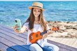 Adorable girl tourist make selfie by the smartphone playing ukulele at seaside