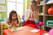 © Krakenimages.com - Teacher and toddler playing with maths puzzle game applauding at kindergarten