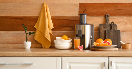 Wall Mural - Modern juicer with fresh fruits and glass of beverage on table in kitchen