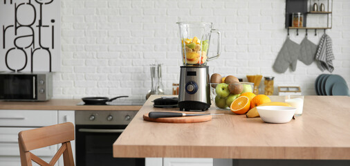 Canvas Print - Modern blender with fresh fruits and cutting board on table in kitchen