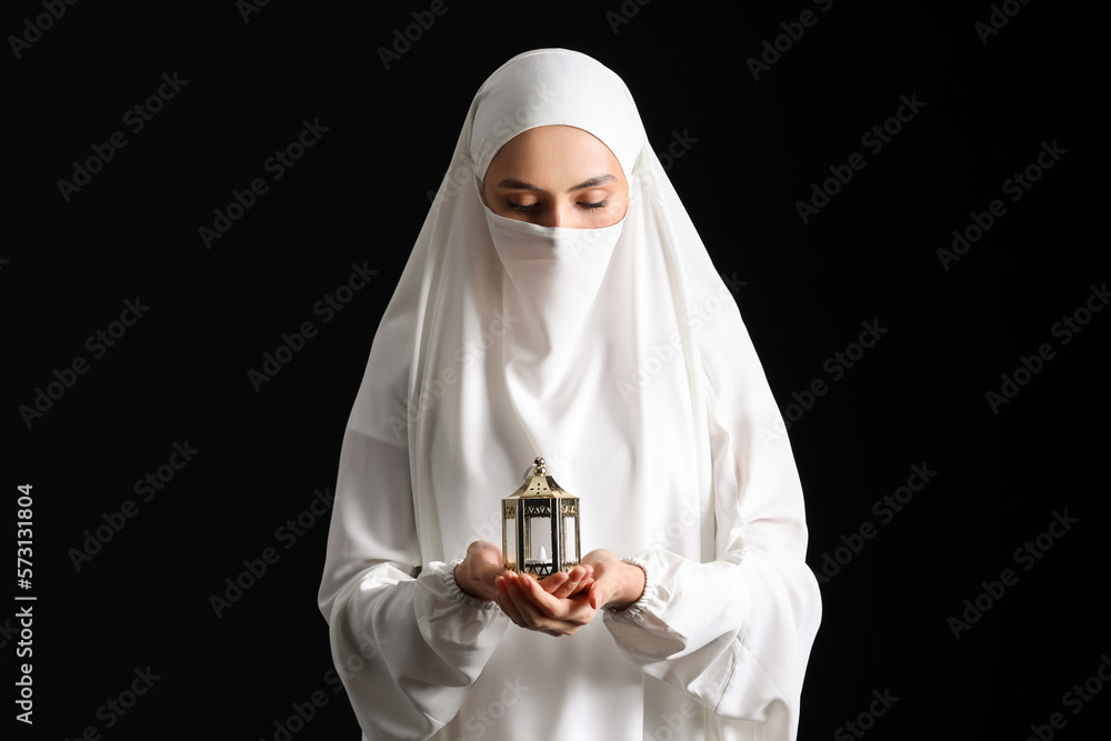 Praying Muslim woman with lantern on black background