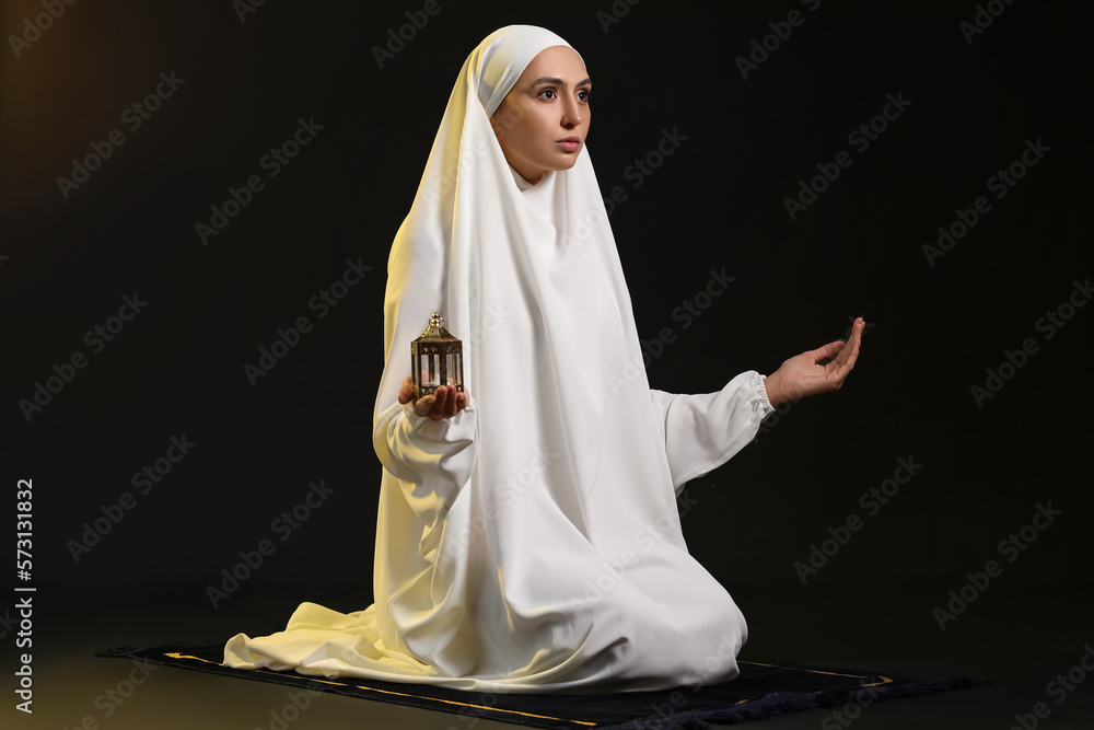Praying Muslim woman on dark background