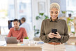 © A.S./peopleimages.com - Black woman in business, smartphone and communication in workplace, reading post and mockup with smile. Meme online, social media manager and content creator for startup, creative and connectivity