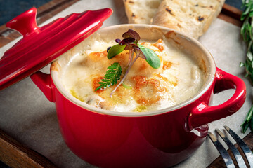 Julienne with mushrooms and cheese, baked in red ceramic cups, close up